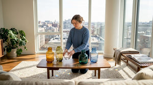 Woman arranging glassware in sunny urban living room